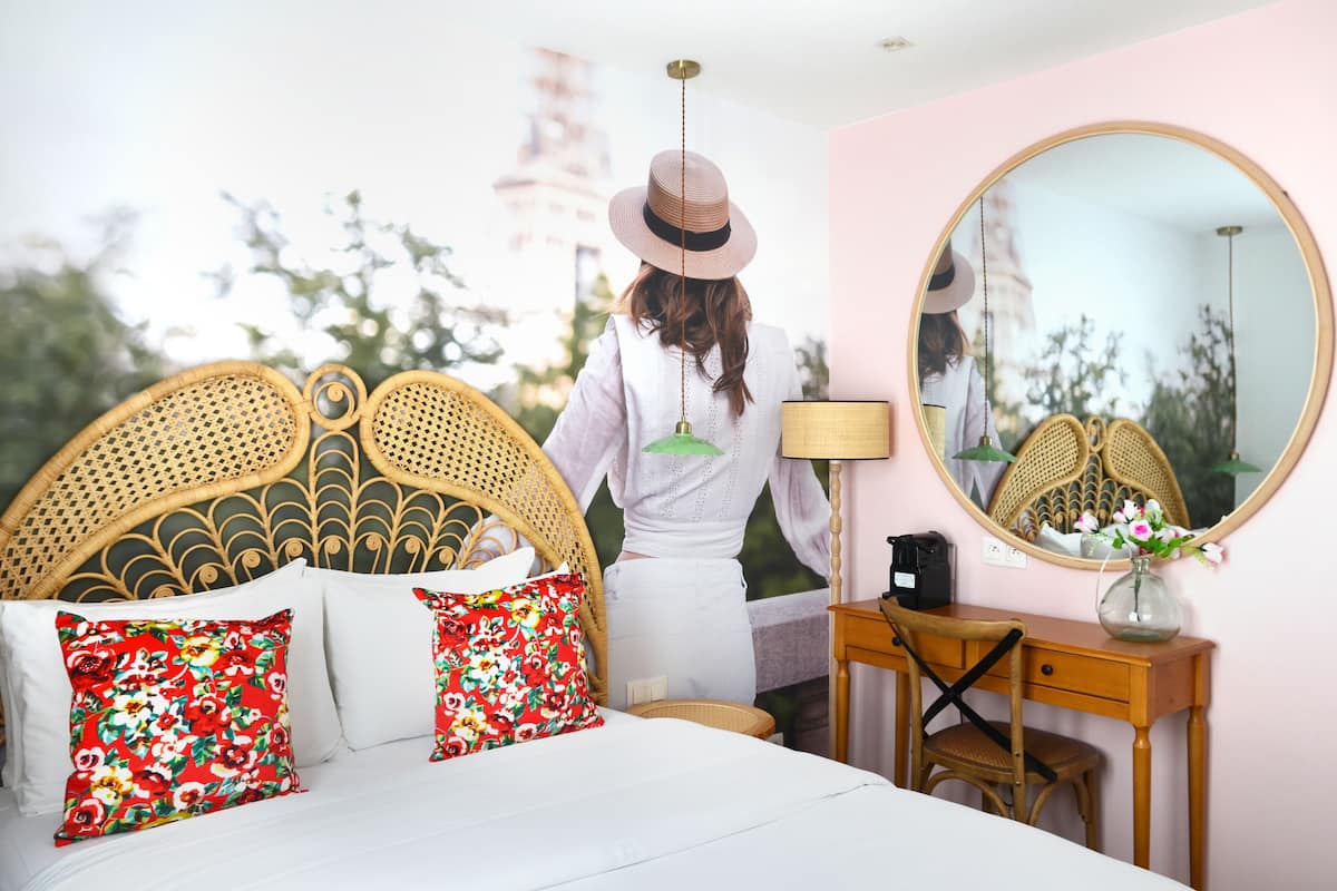 A bedroom with a bed, a dresser, a mirror, and a hanging lamp.