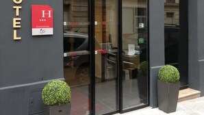 The exterior of Glam's Hotel with a modern design, featuring a large glass entrance and two potted plants at the entrance. - Le Glam's Hôtel (Paris)