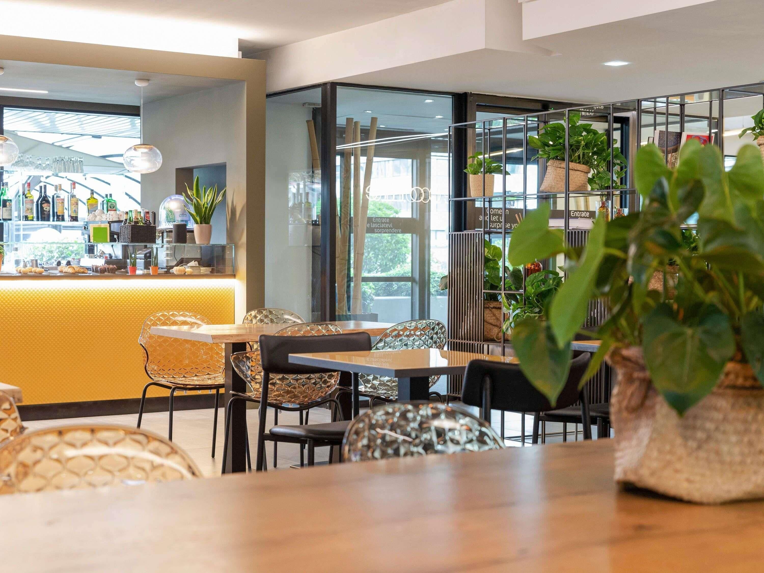 A modern cafe with a bar area, seating, and potted plants.
