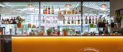 A bar area with a yellow counter, shelves of liquor bottles, and potted plants.