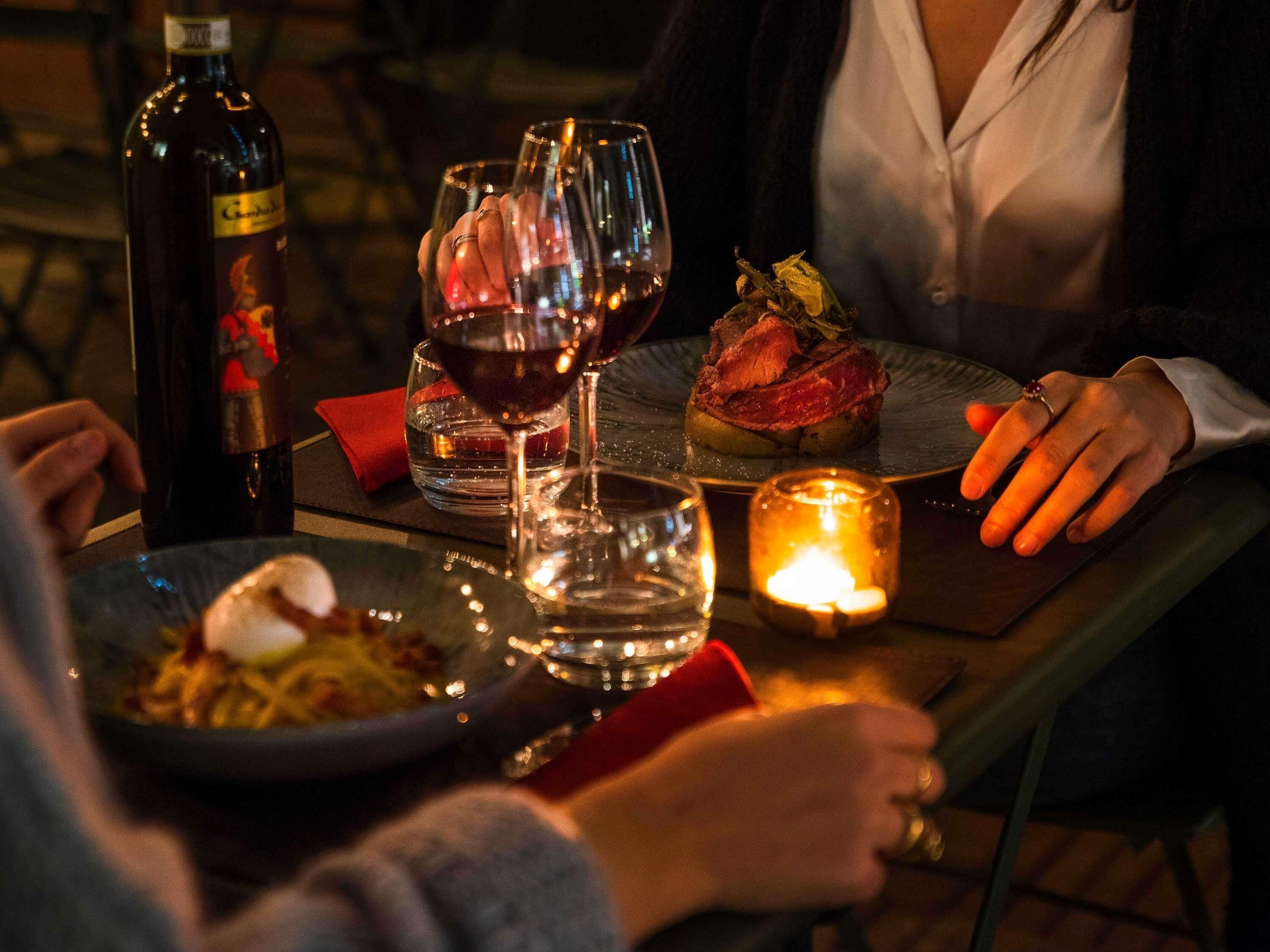 A dining table with wine glasses, a candle, and a plate of food.