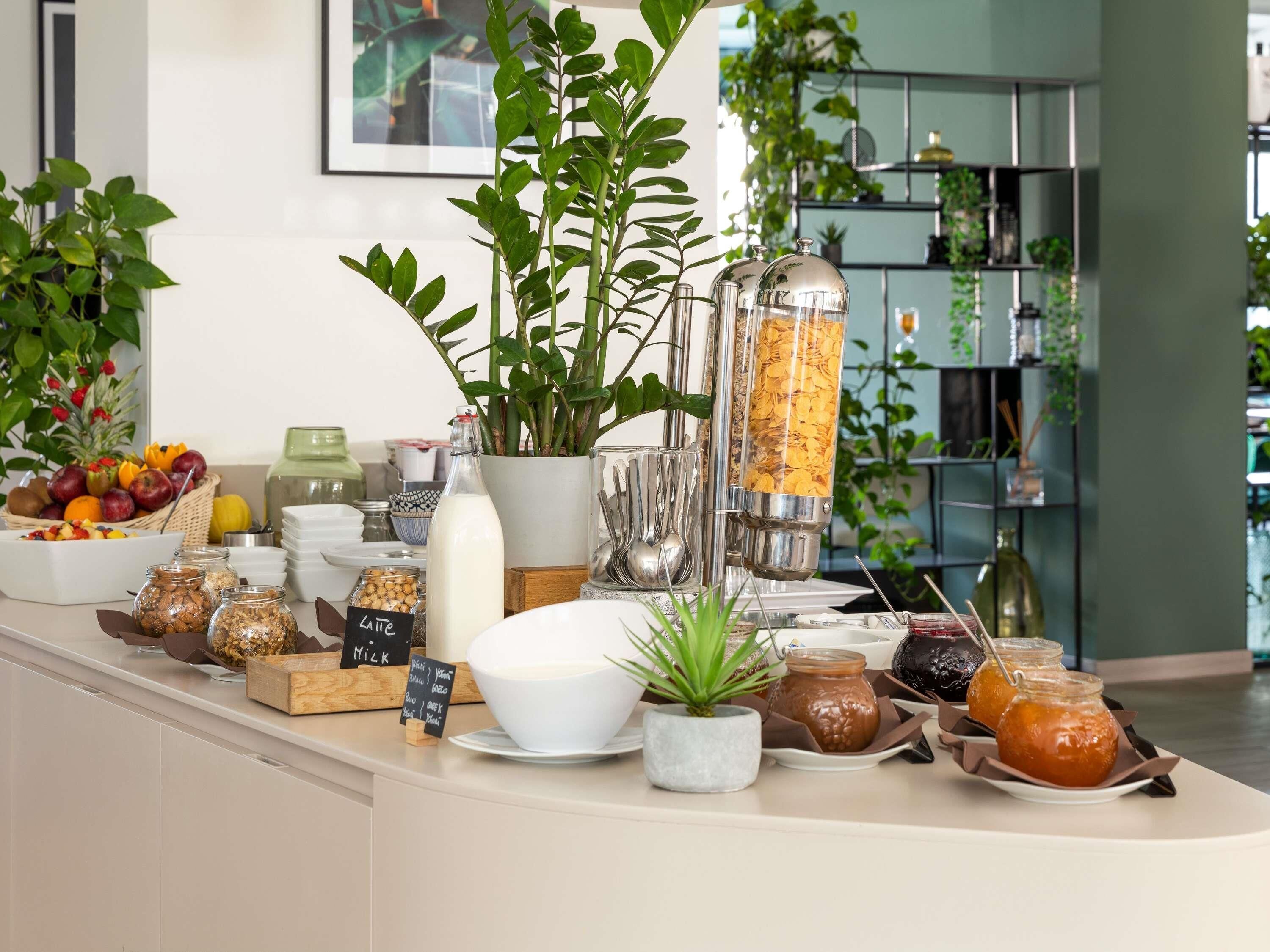 A breakfast buffet with various food items, a milk dispenser, and a coffee machine.
