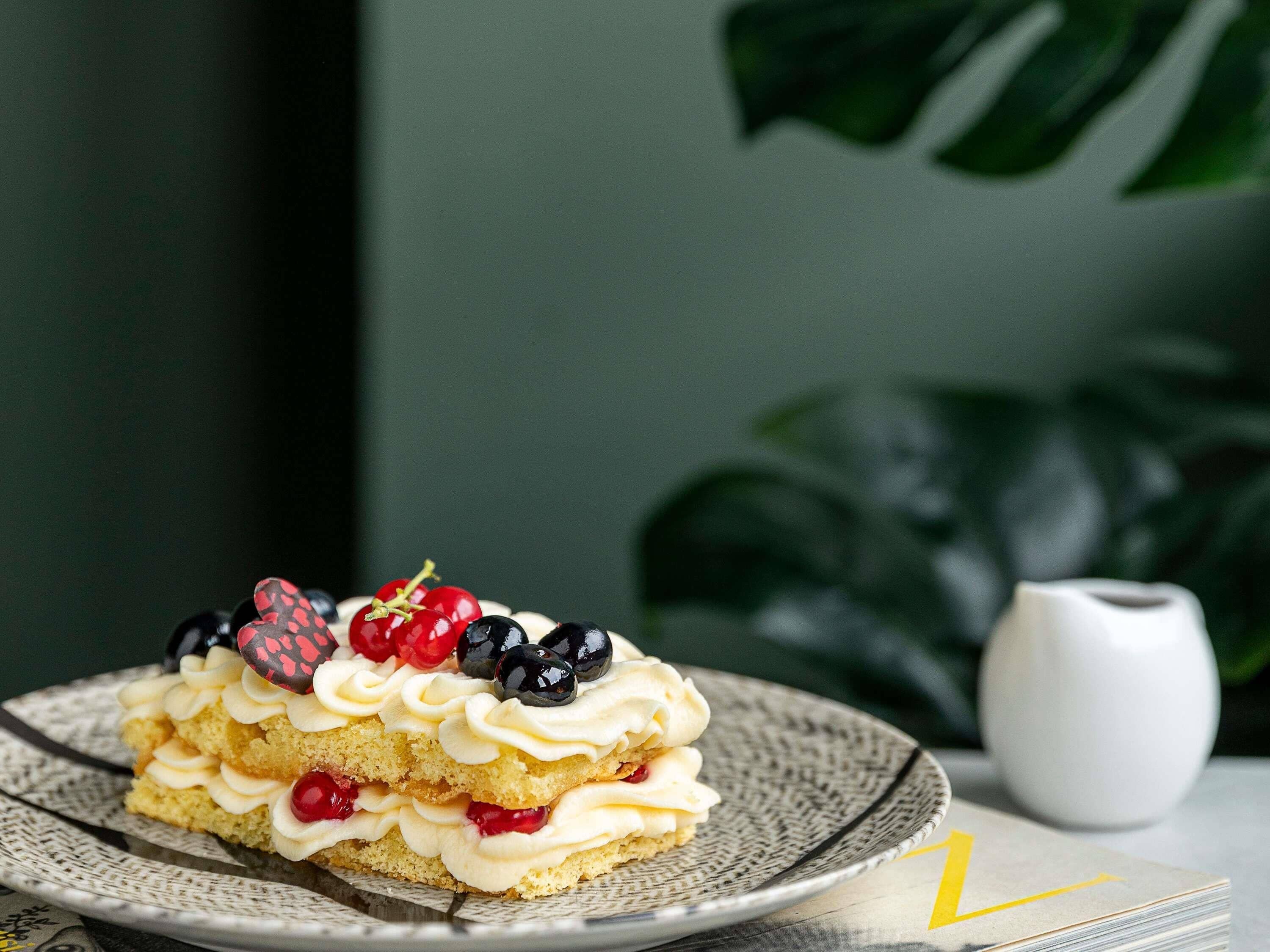 Una porción de pastel en capas con crema y bayas sobre un plato.