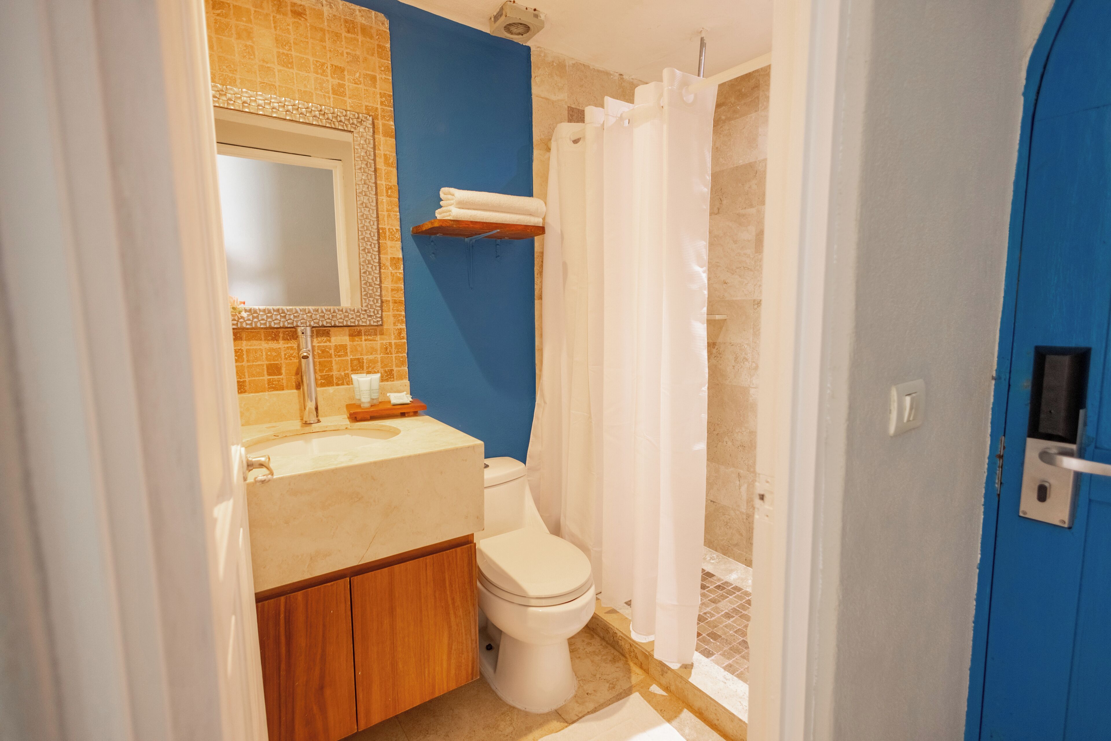 Un baño con inodoro, lavamanos, espejo y cortina de ducha.