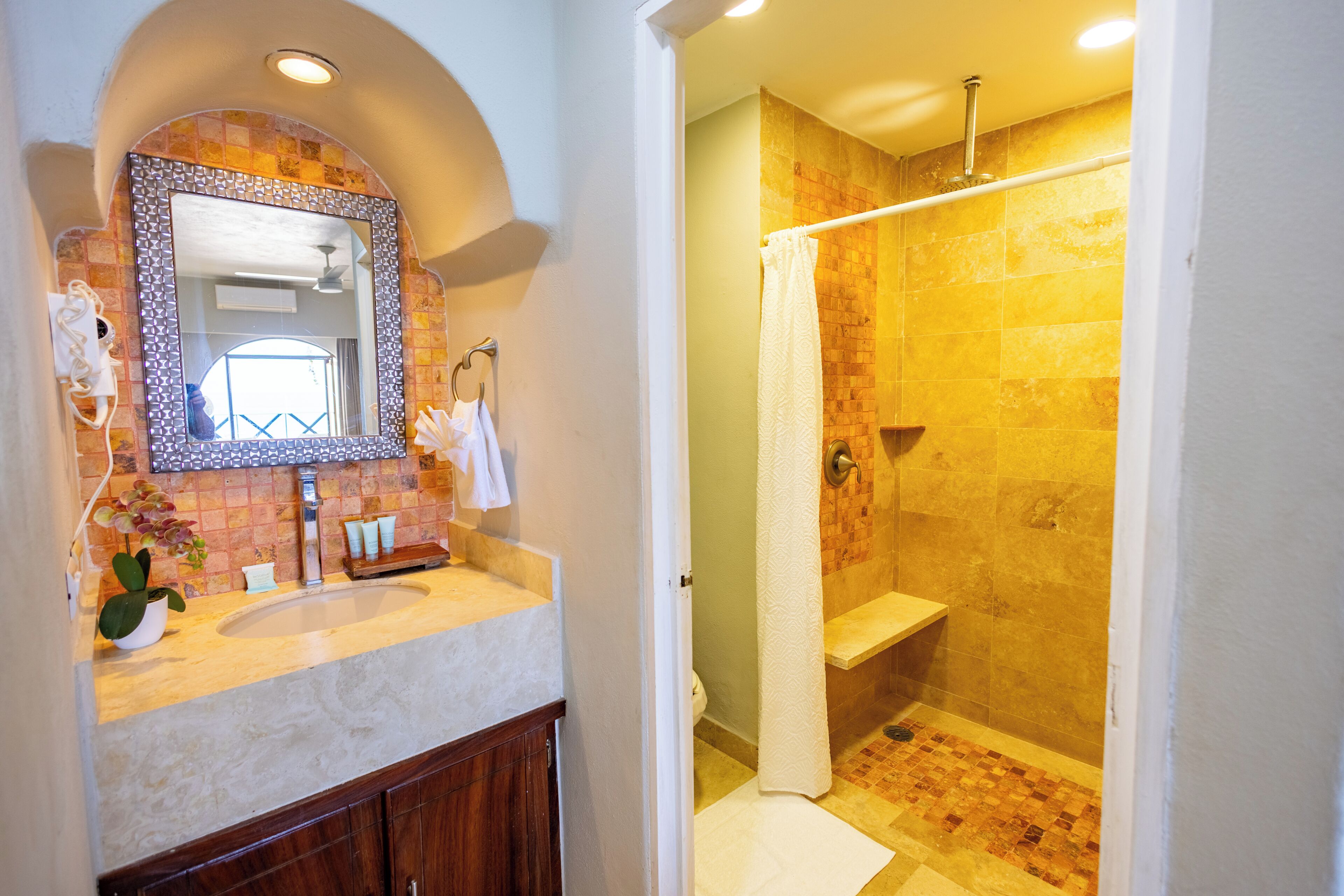 Une salle de bain avec un lavabo, un miroir, une douche et des murs carrelés.