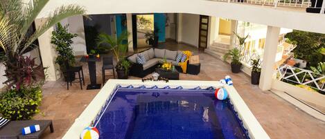 A pool area with a blue tiled floor, a sofa, and a dining table with chairs.