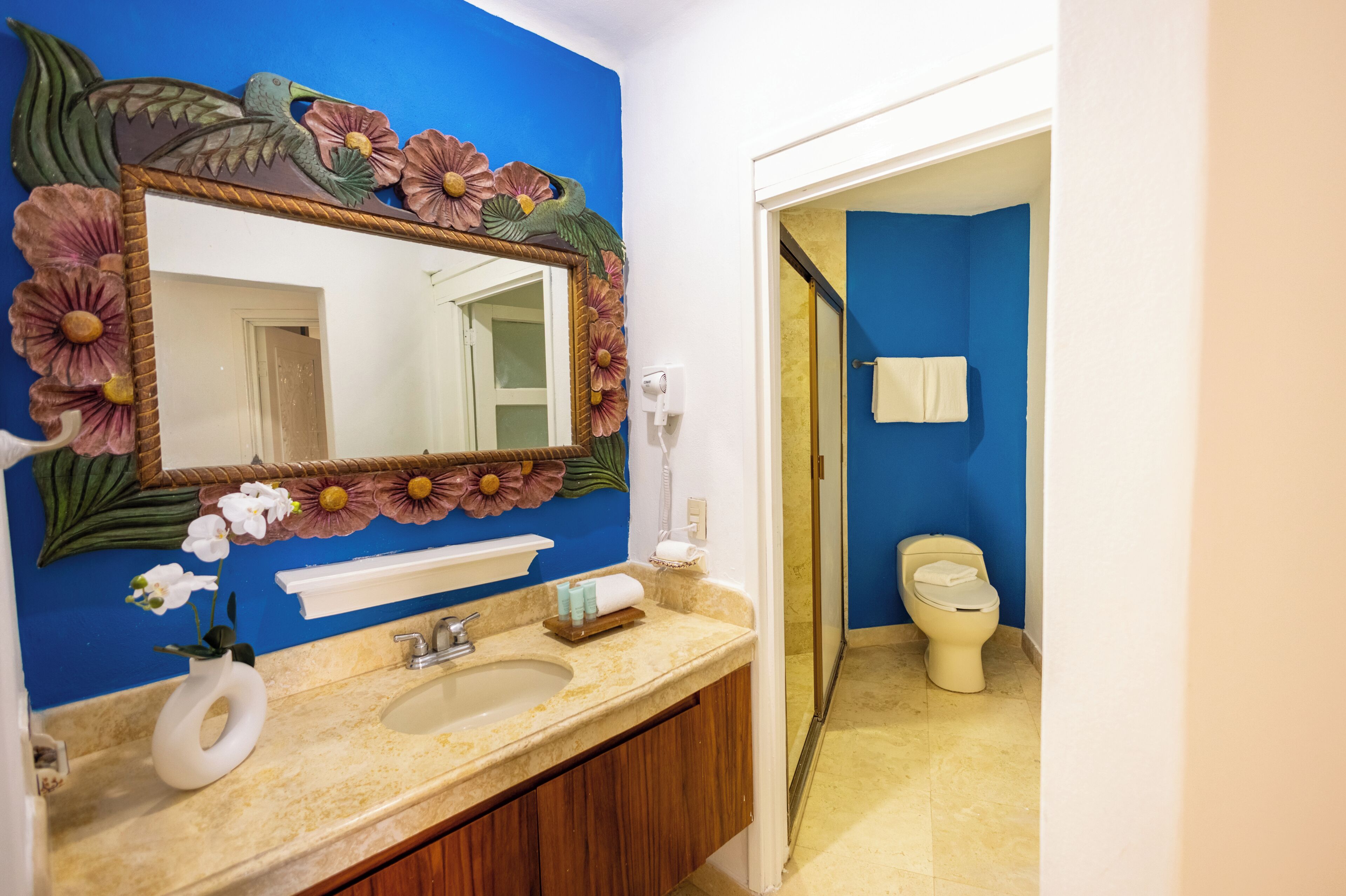 Un baño con pared azul, un lavabo con espejo y un inodoro.