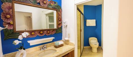 Un baño con pared azul, un lavabo con espejo y un inodoro.