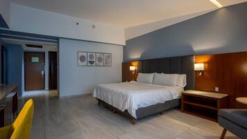 Una habitación de hotel moderna con una cama grande, lámparas de noche, un cabecero de madera y una mesita de noche pequeña de madera.