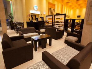 A lobby with sofas, tables, and a Starbucks sign. - Holiday Inn Puebla Finsa by IHG (Puebla)