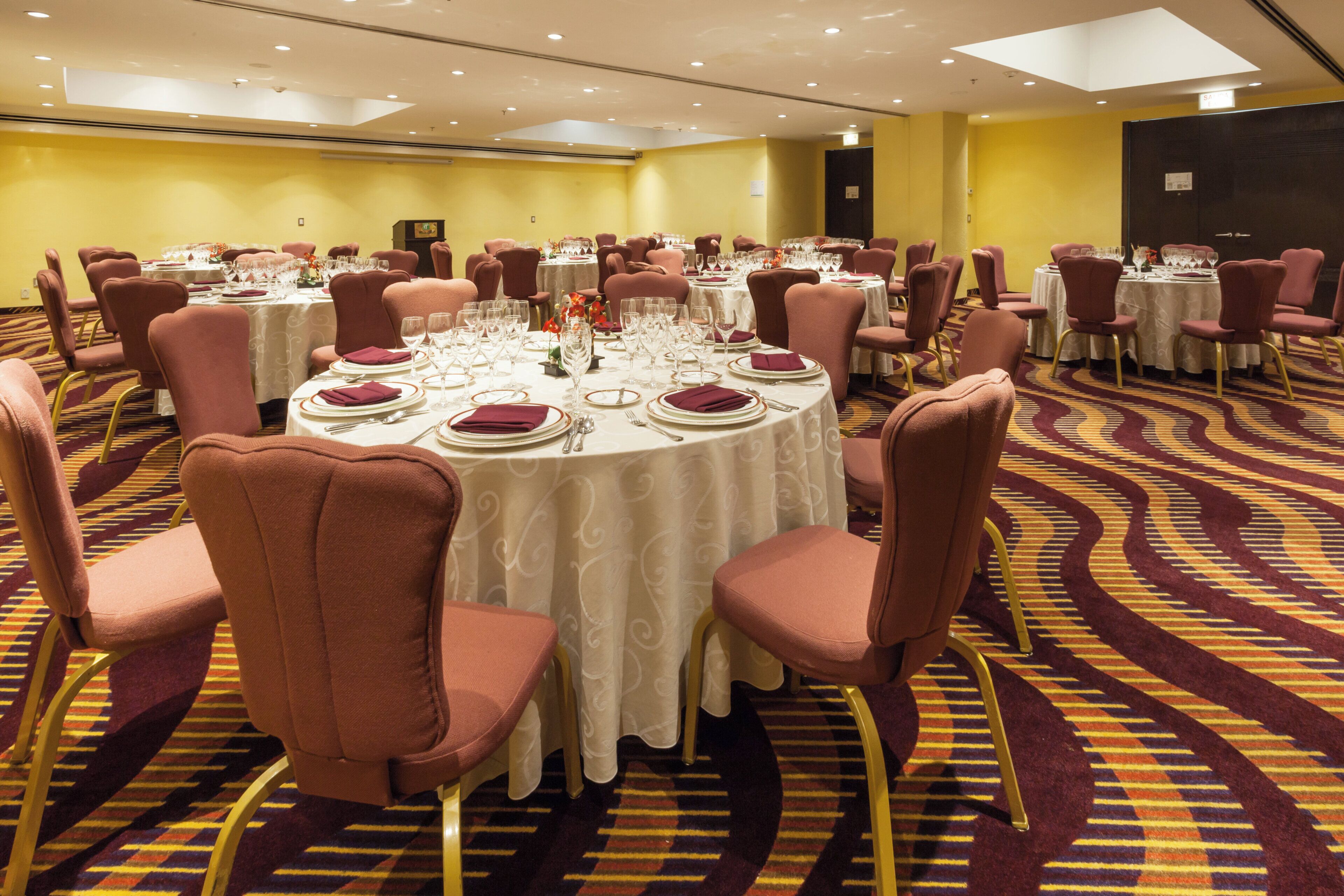A conference room with round tables, chairs, and a carpeted floor.