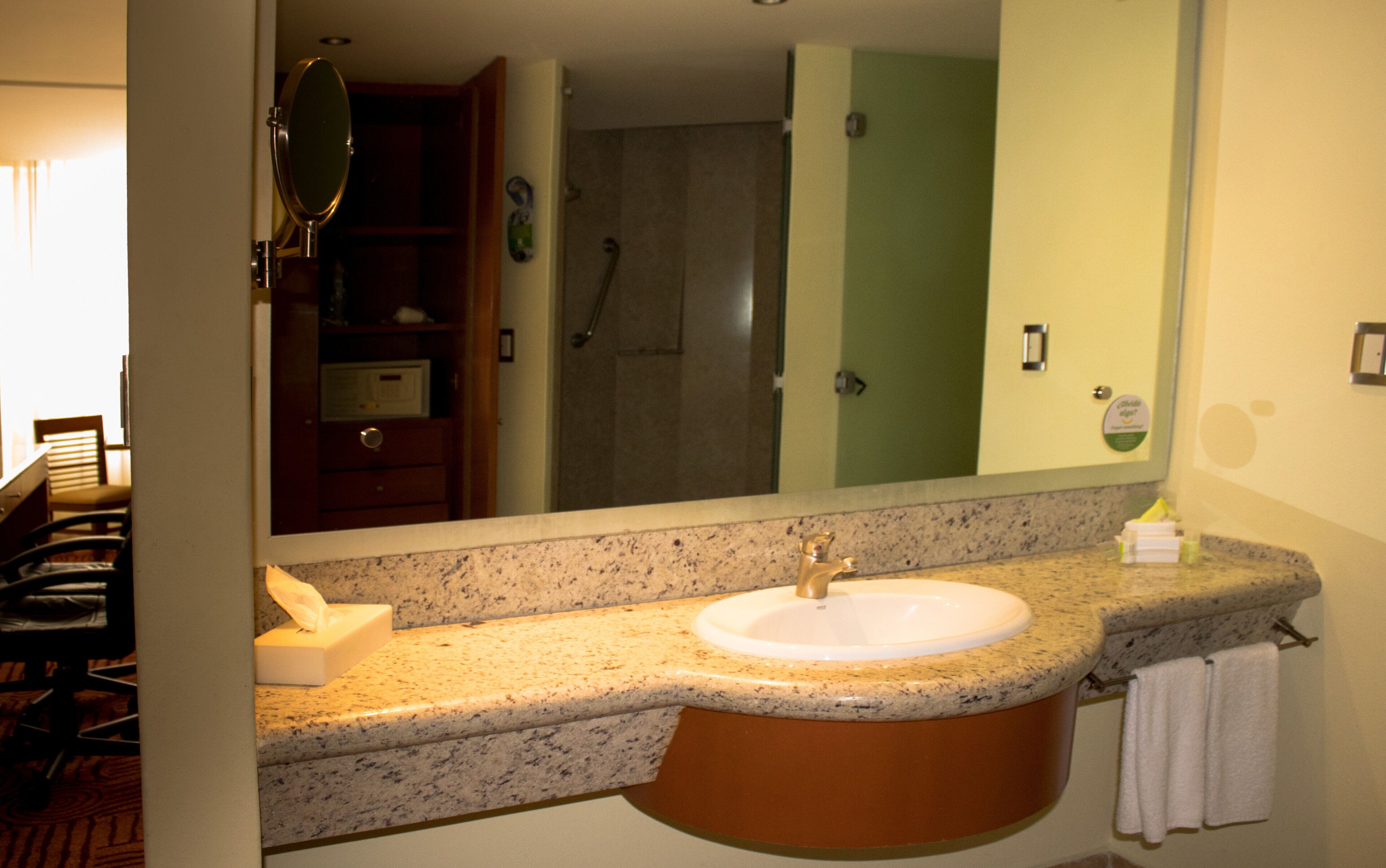 A bathroom with a granite countertop, a sink, and a mirror.