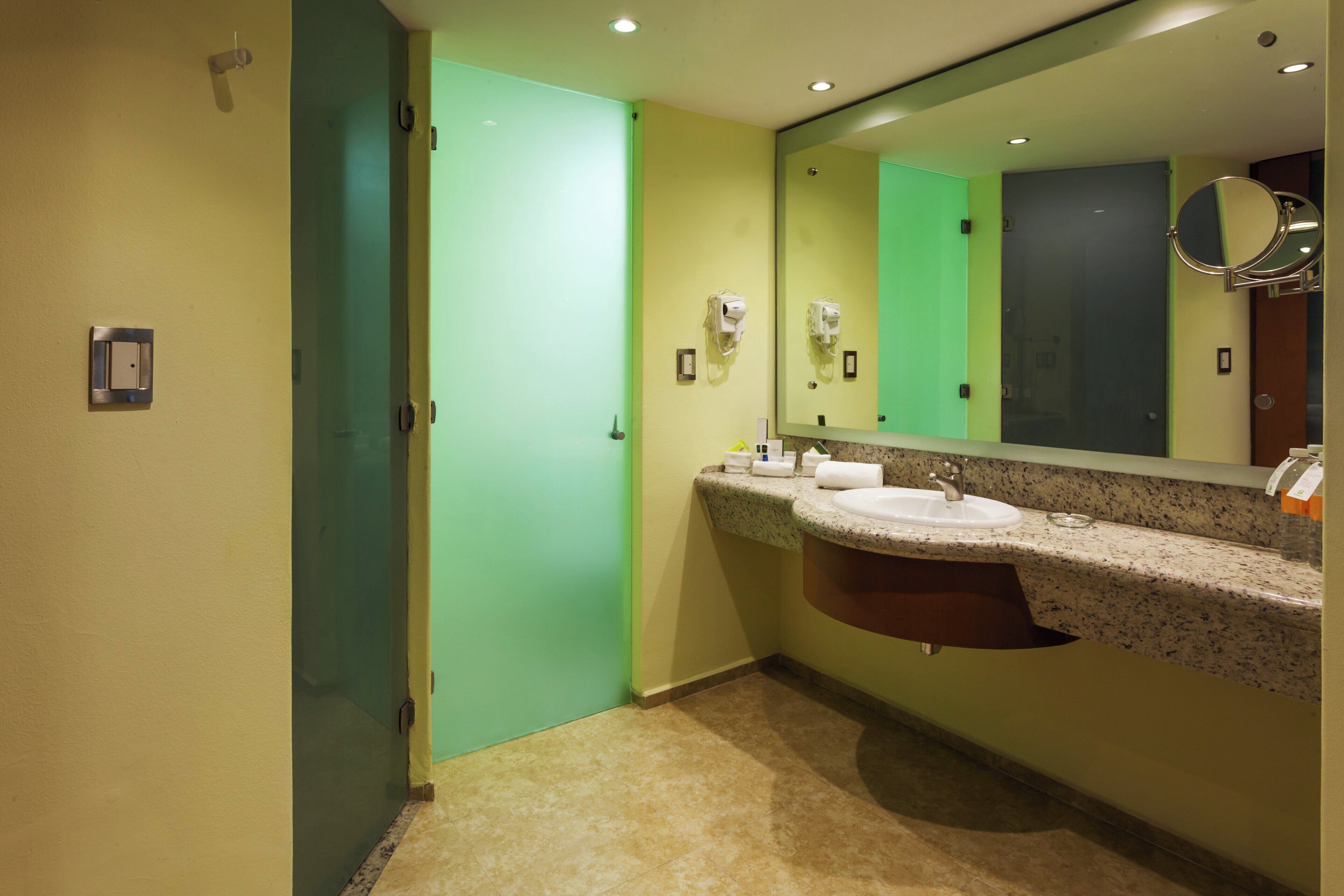 Ein Badezimmer mit einer grünen Tür, einem Waschbecken mit Spiegel darüber und einem Handtuchspender.