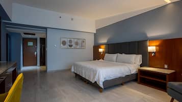 Quarto de hotel moderno com cama, mesas de cabeceira, escrivaninha e cadeira.