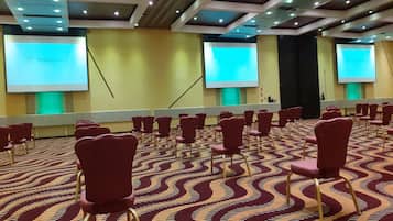 A conference room with rows of red chairs, a patterned carpet, and a ceiling with recessed lighting.