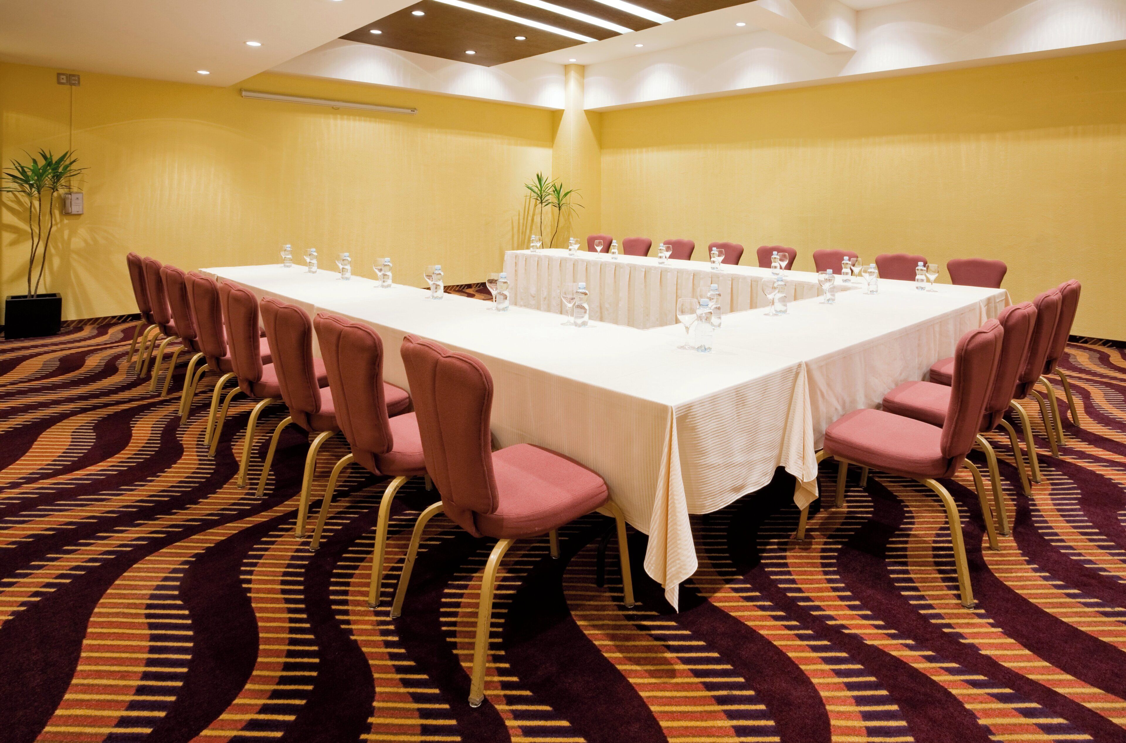 Une salle de conférence avec une longue table, de nombreuses chaises et des bouteilles d’eau.