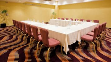 Une salle de conférence avec une longue table, de nombreuses chaises et des bouteilles d’eau.