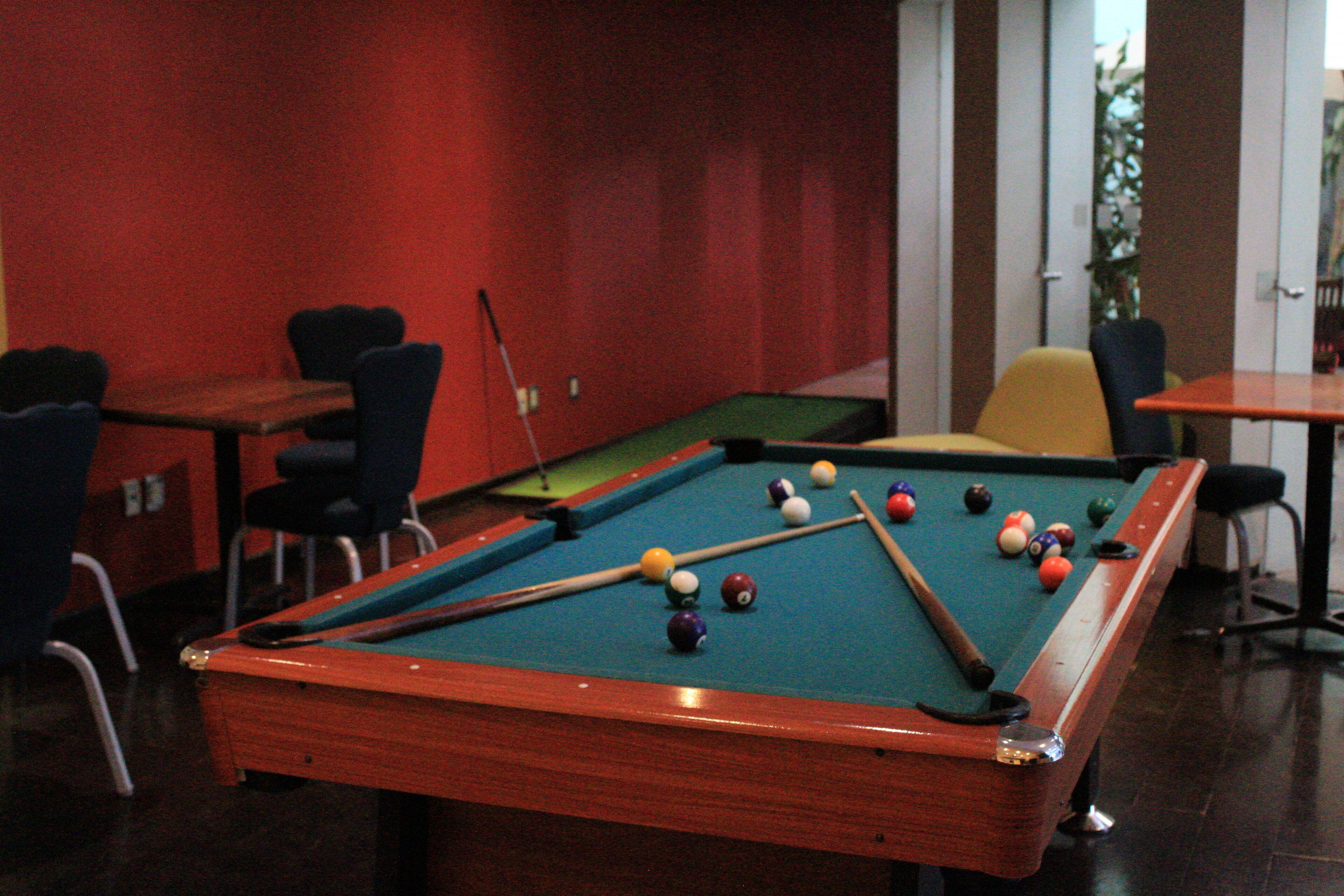 A pool table in a room with red walls and a door leading to a balcony.
