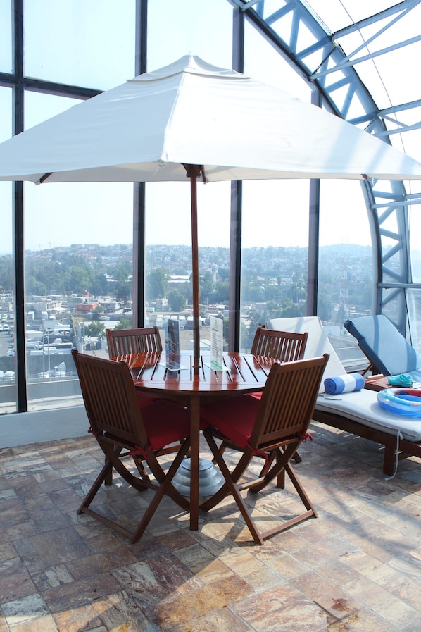 A dining area with a table, chairs, and a white umbrella.