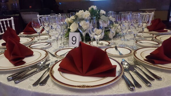 A table set for a formal dining event with numbered place settings, silverware, and wine glasses.