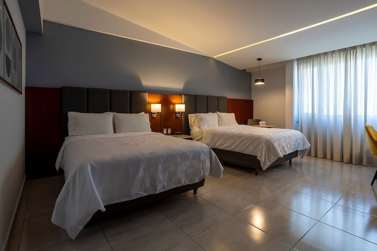 A hotel room with two beds, a large window with curtains, and a modern design.
