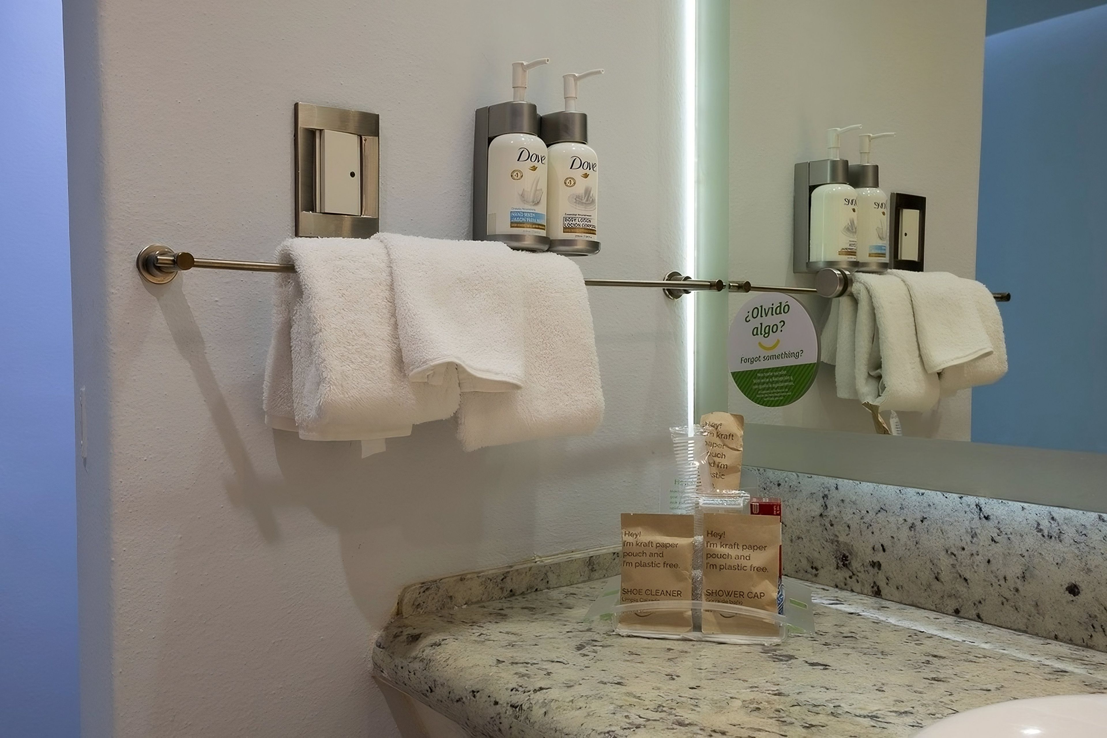 Une salle de bain dotée d’un comptoir en marbre, d’un porte-serviettes avec des serviettes blanches et d’un miroir qui reflète l’intérieur de la salle de bain.