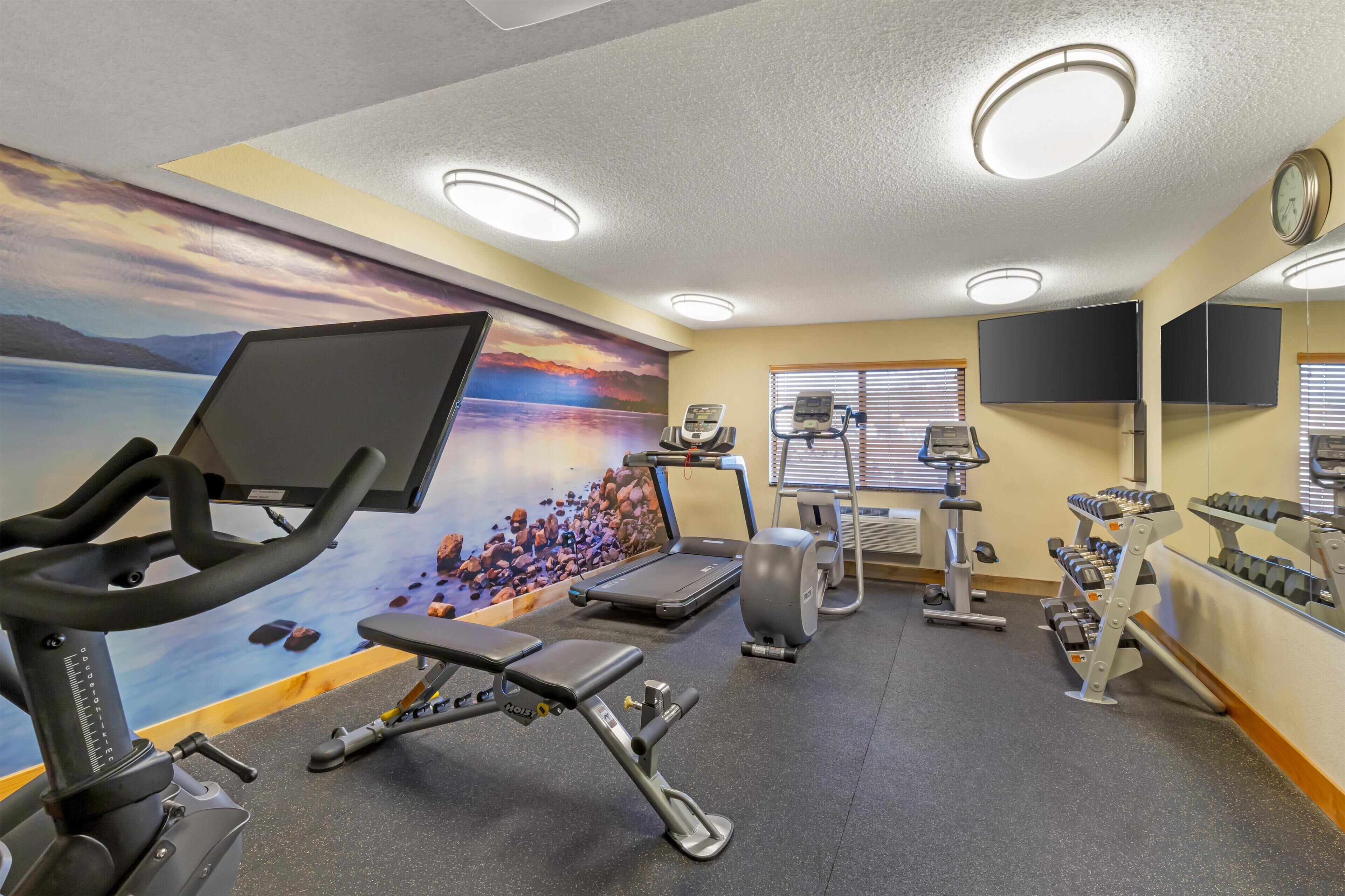A gym with exercise equipment, a treadmill, a stationary bike, and a rowing machine.