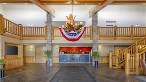 A spacious lobby with a wooden reception desk, a chandelier, and a staircase leading to an upper level. - Best Western Plus McCall Lodge & Suites (McCall)