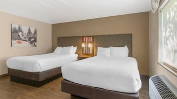 A hotel room with two beds, a large window, and a wall-mounted heater.