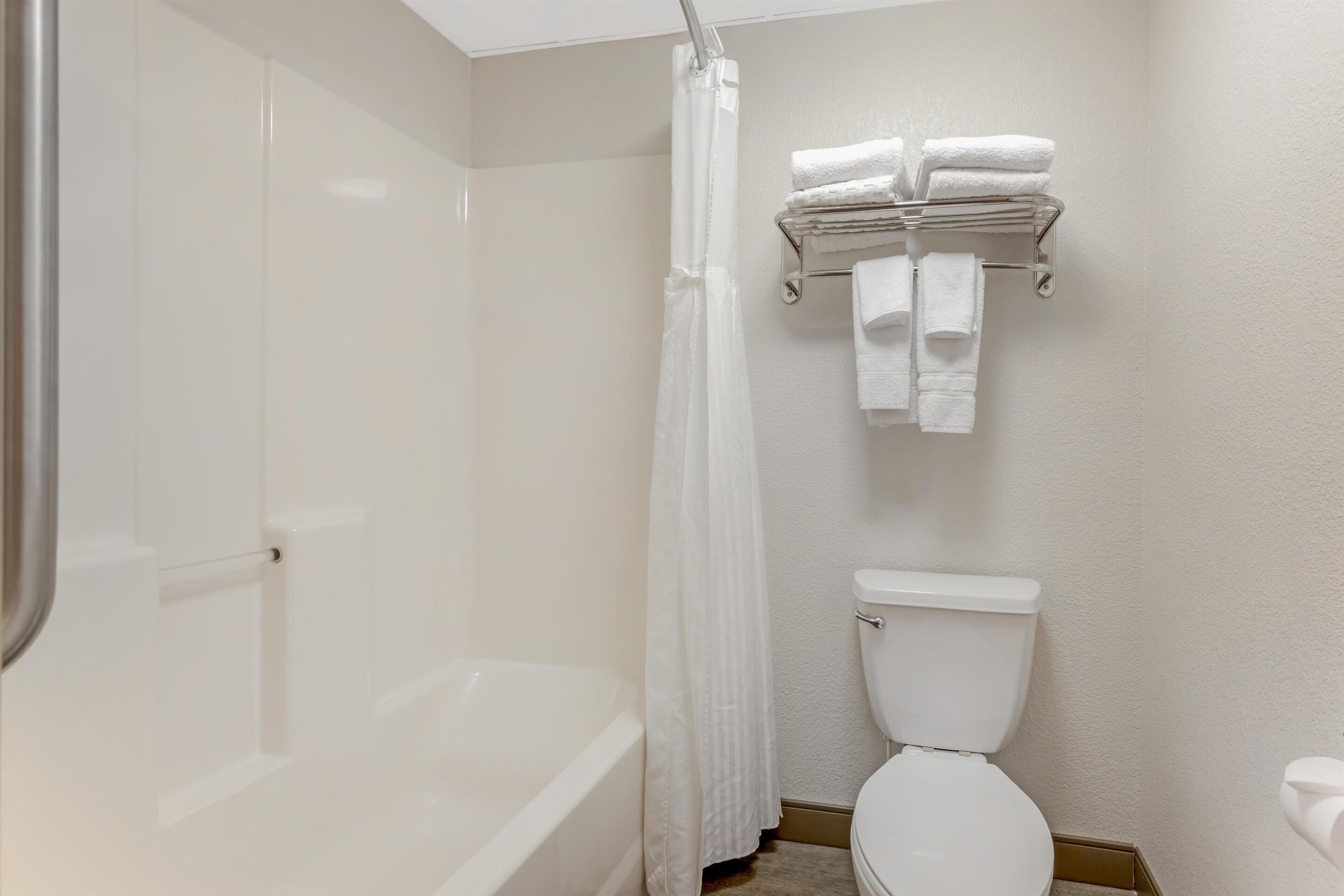 A bathroom with a bathtub, toilet, and a towel rack with folded towels.