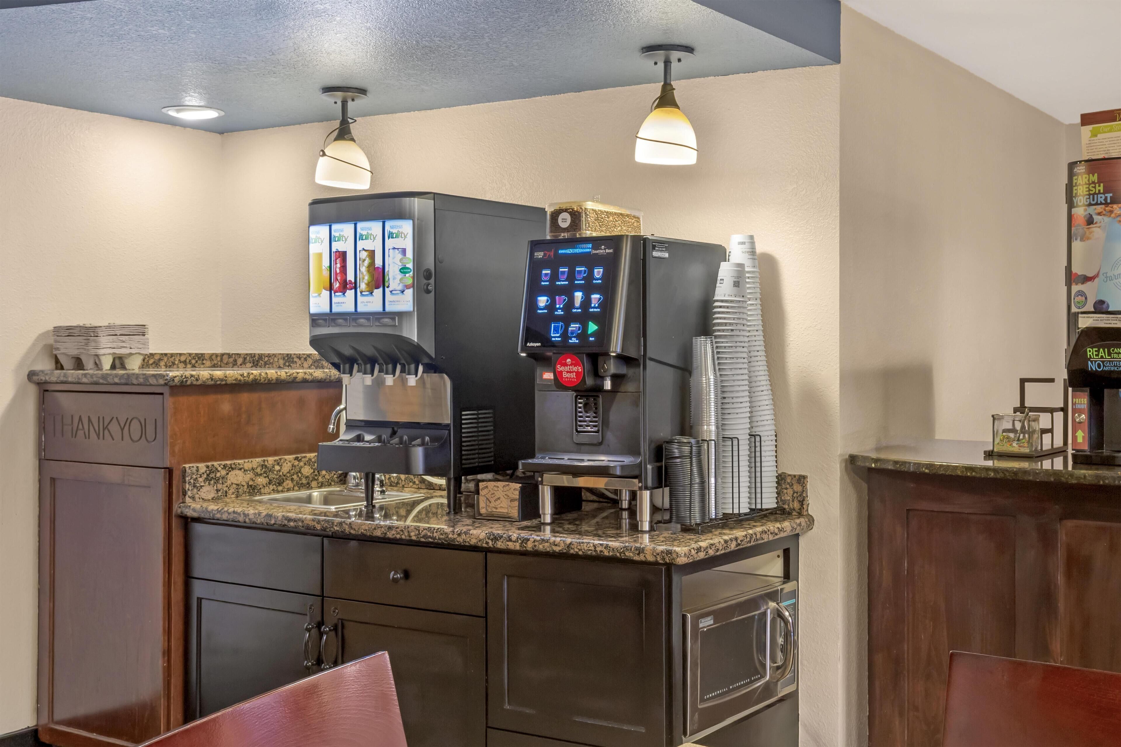 A self-service beverage station with a coffee machine, a refrigerated drink dispenser, and a coffee press.