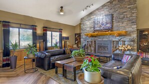 A cozy living room with a stone fireplace, leather sofas, and large windows with curtains. - Best Western Plus McCall Lodge & Suites (McCall)