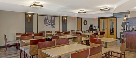 A restaurant with multiple tables and booths, a coffee machine, and a wall-mounted clock.