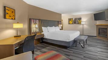 Quarto de hotel com cama, escrivaninha, cadeira, banco e obras de arte nas paredes.