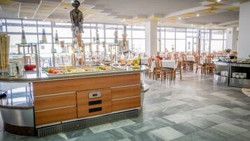 A spacious dining area with a central island, multiple tables, and chairs.