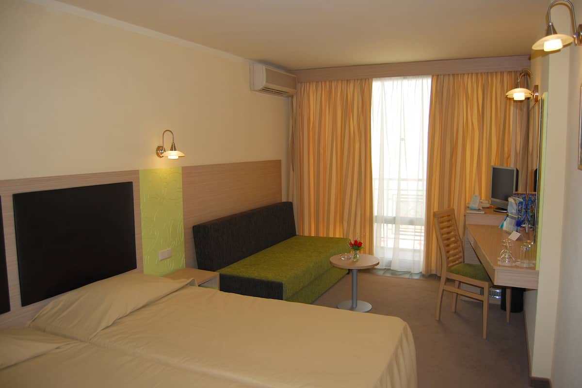 A hotel room with two beds, a small table, a chair, and a desk with a computer.