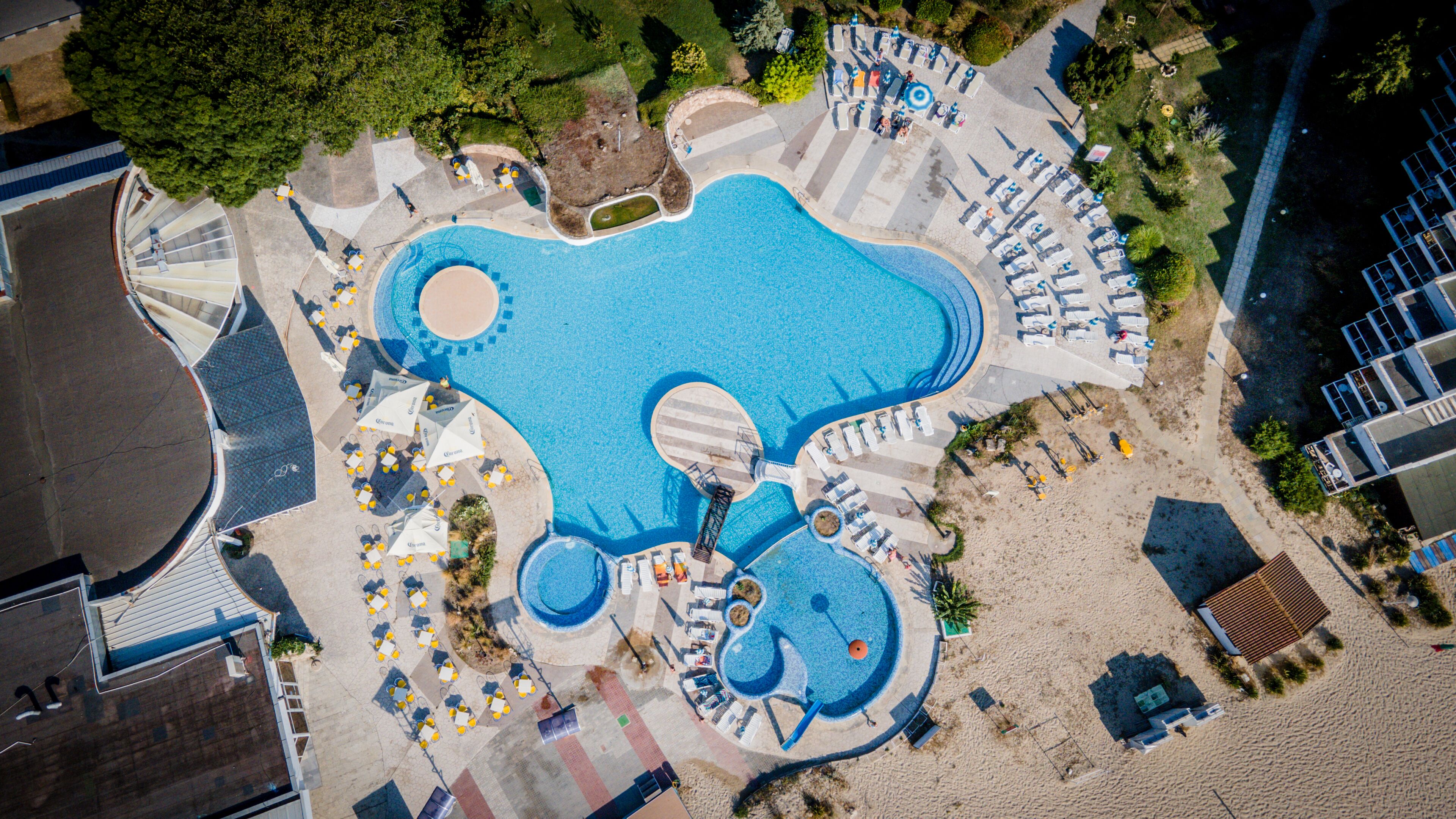 Una piscina al aire libre de temporada, sombrillas, tumbonas