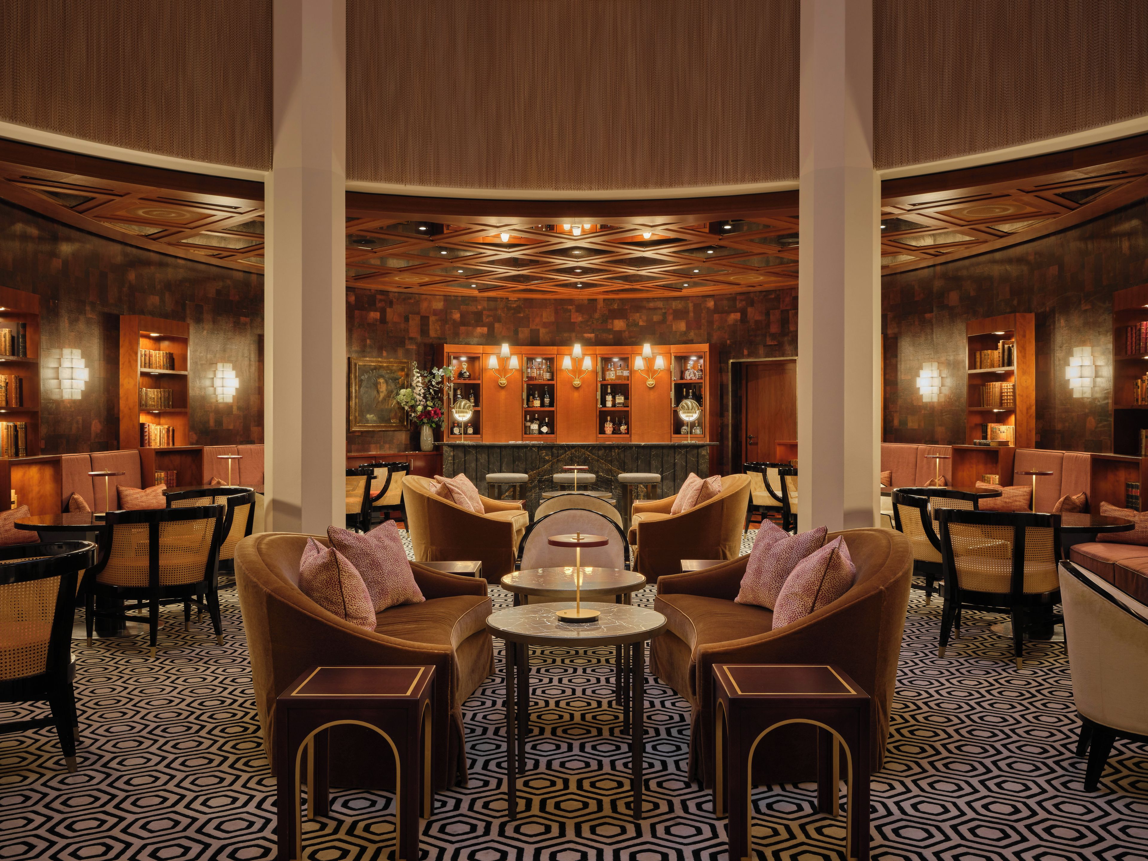 A lobby with a bar area, seating arrangements, and bookshelves.
