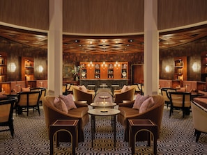 A lobby with a bar area, seating arrangements, and bookshelves.