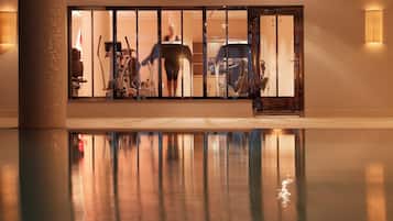 A gym with exercise equipment and a reflection in the pool.