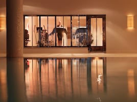 Ein Fitnessraum mit Trainingsgeräten und einem Spiegelbild im Pool.