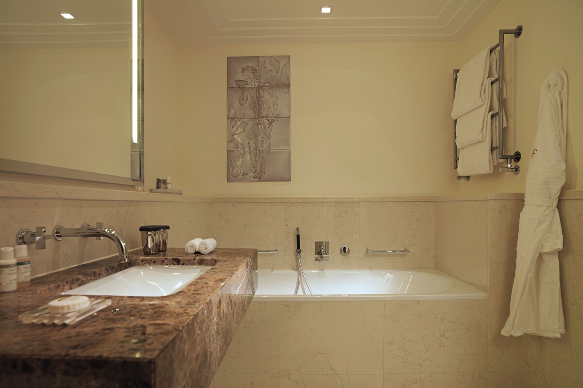A bathroom with a marble sink, a bathtub, and a towel rack.