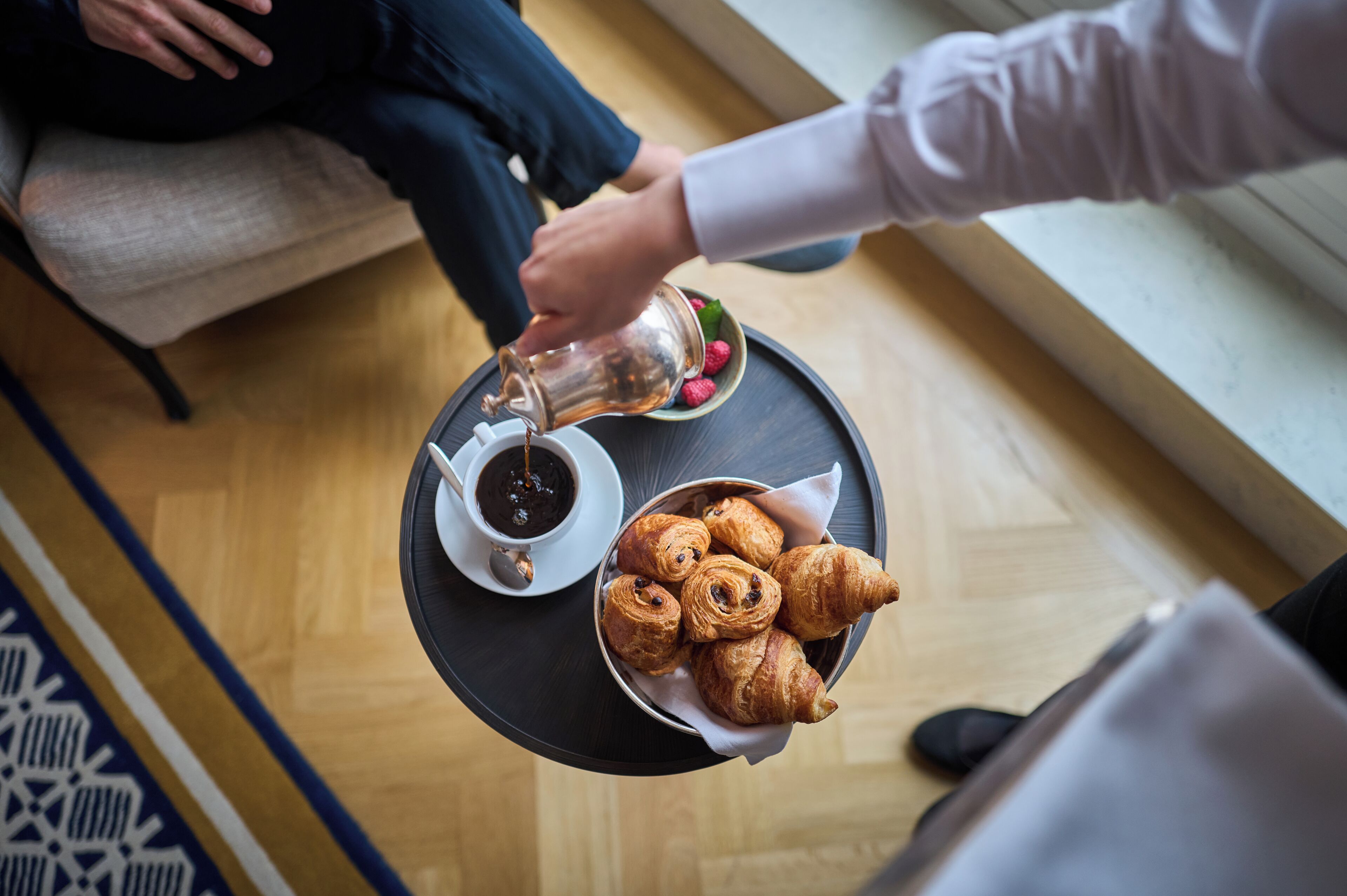 En bakke med croissanter og en kop kaffe på et bord.