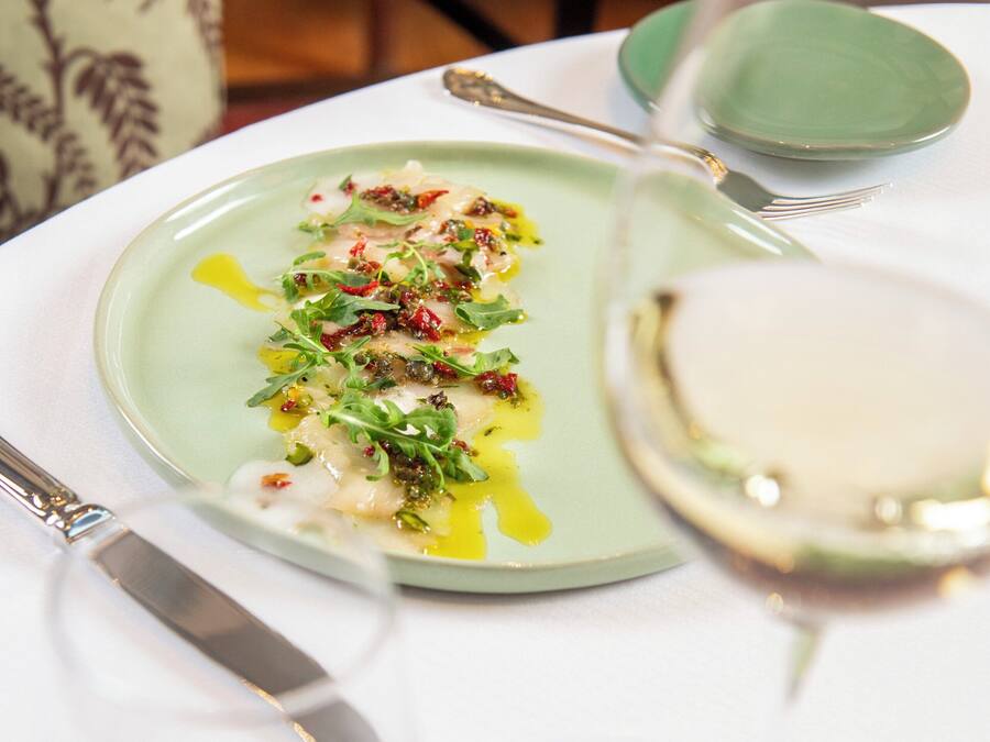 Una mesa de comedor con un plato de comida, una copa de vino y un plato verde.