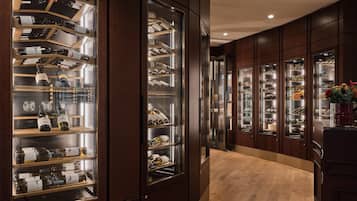Un pasillo de hotel de lujo con paneles de madera y vitrinas de vidrio que exhiben vino y zapatos.