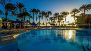A swimming pool with lounge chairs and umbrellas, surrounded by palm trees. - Regina Resort & Aqua Park Hurghada (Hurghada)