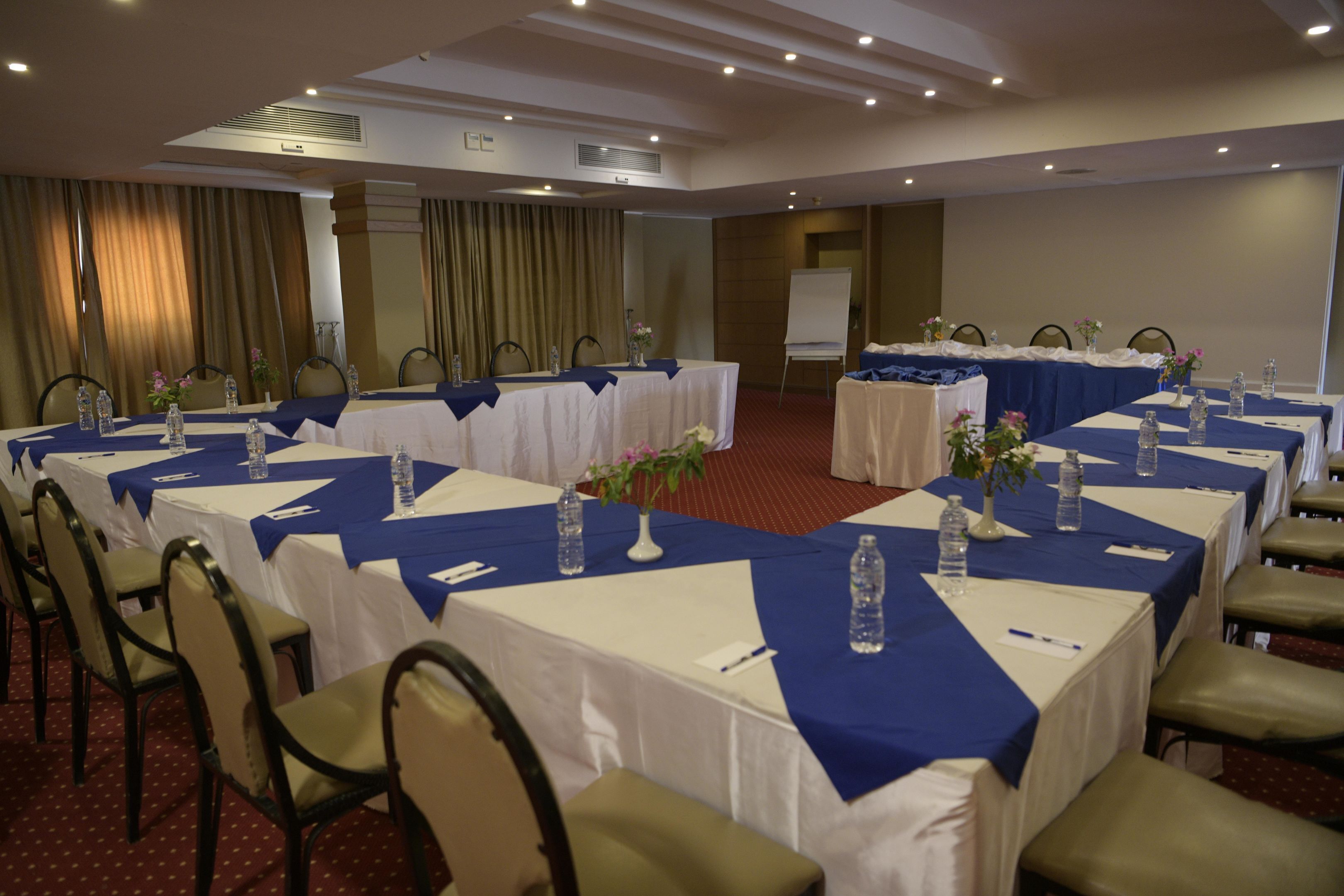 Un salón de conferencias con varias mesas, sillas y una pizarra.