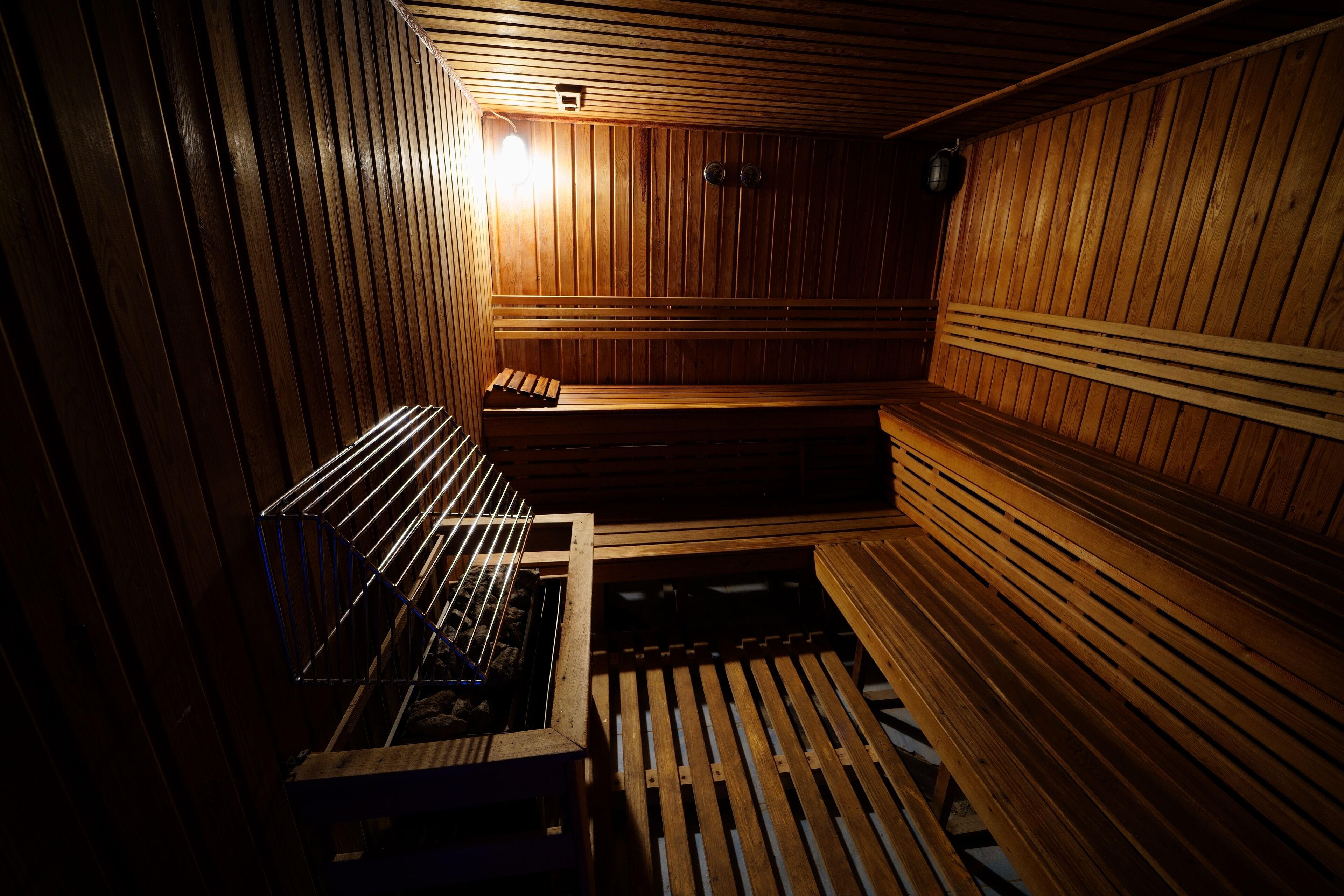 A sauna with wooden benches and a bench with a towel rack.