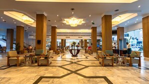 A spacious lobby with wooden pillars, a central floral arrangement, and a geometric floor pattern. - Regina Resort & Aqua Park Hurghada (Hurghada)