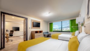 A hotel room with a bed, a desk, a chair, a TV, and a window with a view of a cityscape. - La Joya Pachuca (Pachuca)
